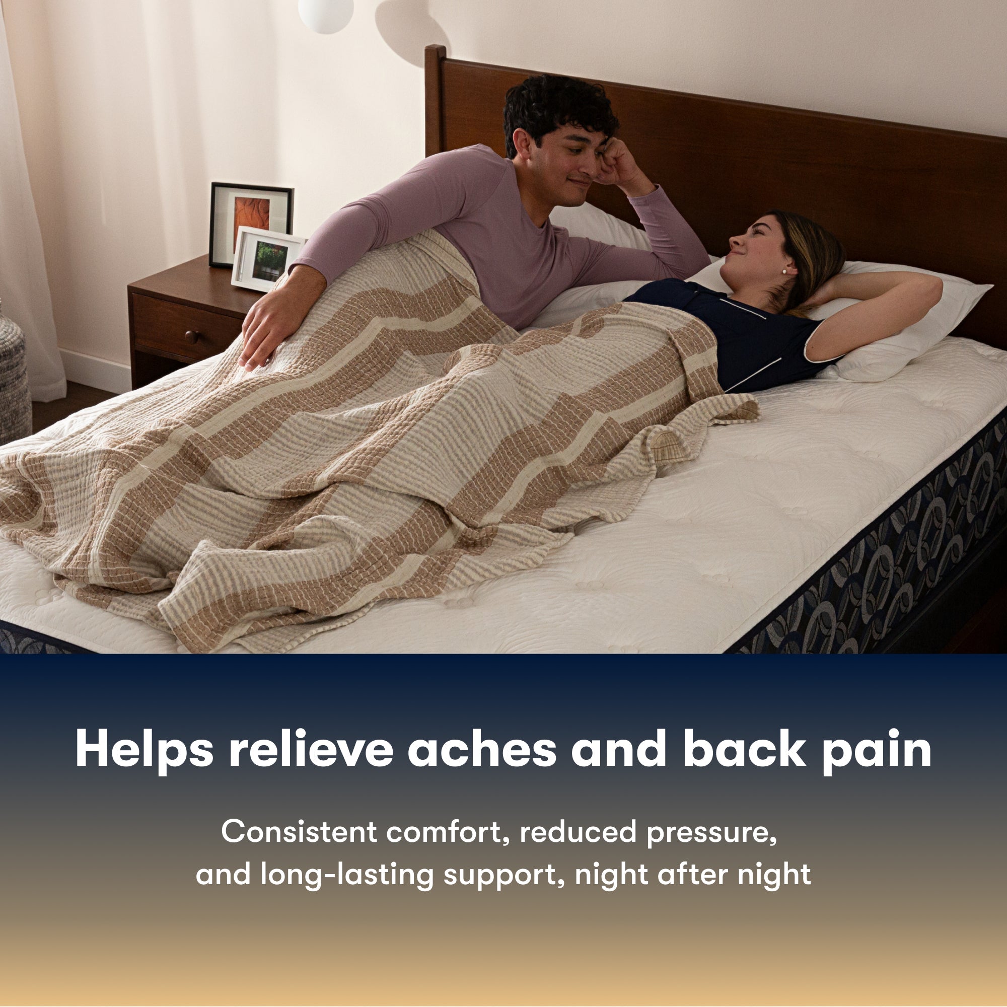 Couple lying on a Serta Perfect Sleeper Hybrid Firm mattress under a striped blanket with text about back pain relief.