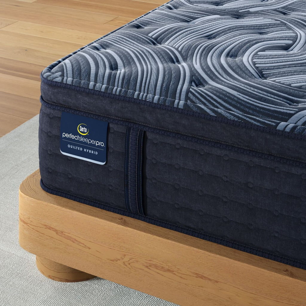 Corner of Perfect Sleeper Pro Valais Plush Pillow Top mattress sitting in a brown bedframe || Level: Level 3 || Feel: Plush Pillow Top
