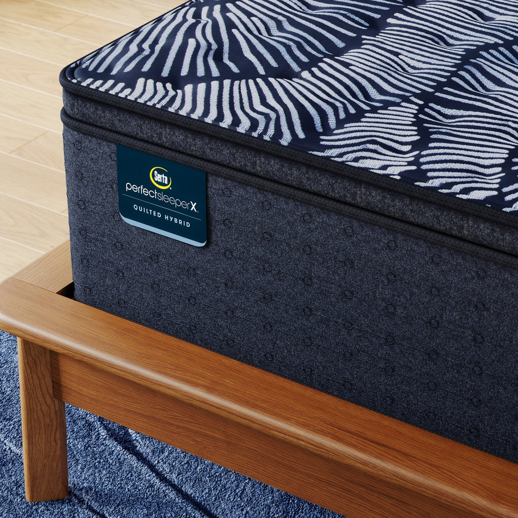 Corner of Perfect Sleeper X Quilted Hybrid Lexton Medium Pillow Top Mattress sitting in a brown bedframe || feel: Medium Pillow Top || level: Level 1