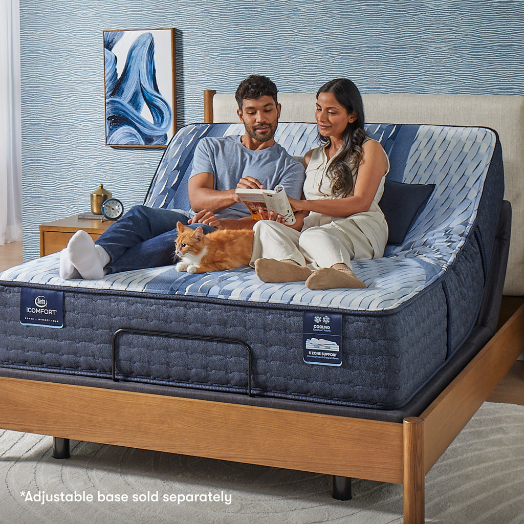Woman and man sitting on a Serta iComfort mattress with a cat by their feet in between them reading a crossword puzzle || feel: plush || level: Standard - 13"
