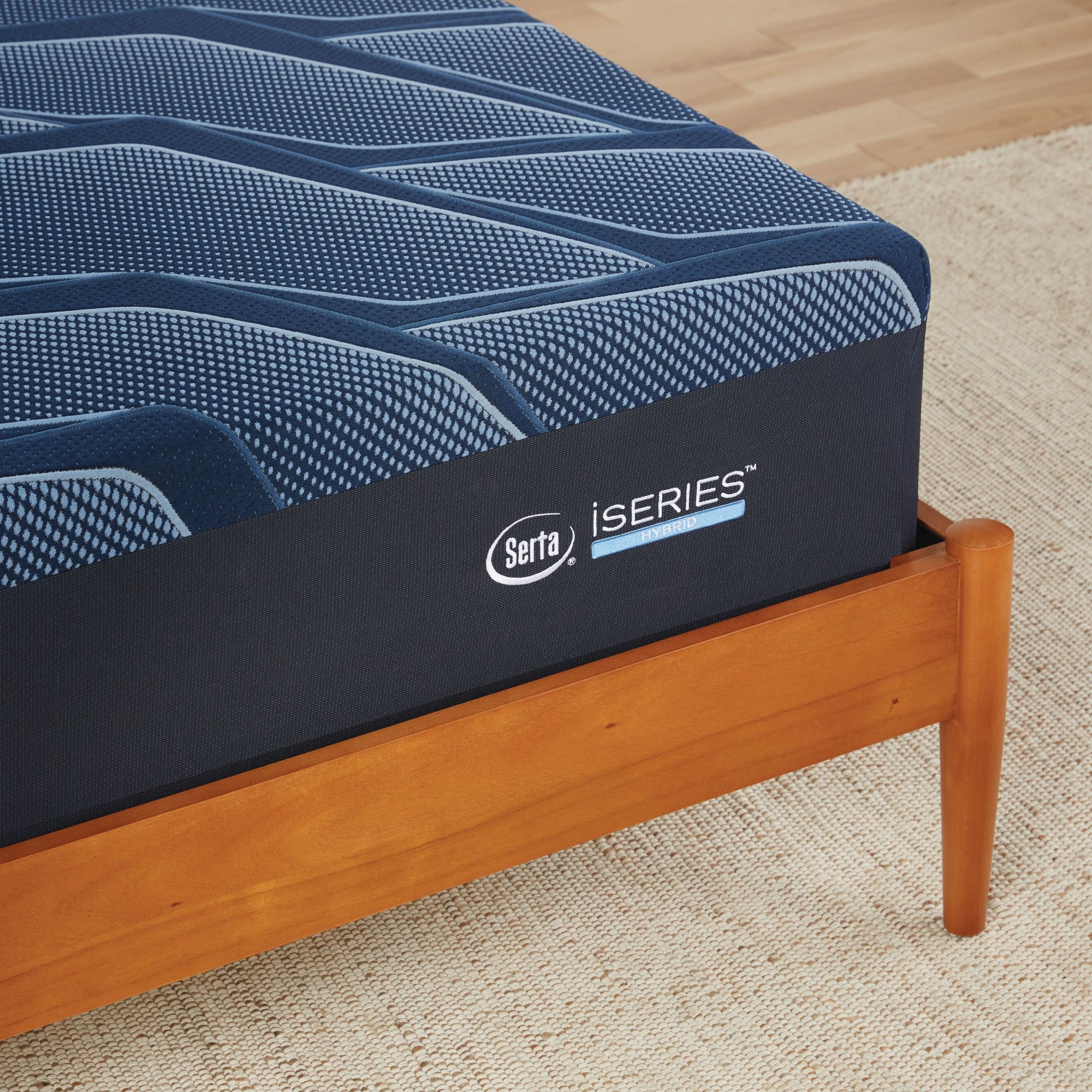 A corner of a wooden bed with a Serta iSeries firm blue mattress||feel: firm||level: enhanced