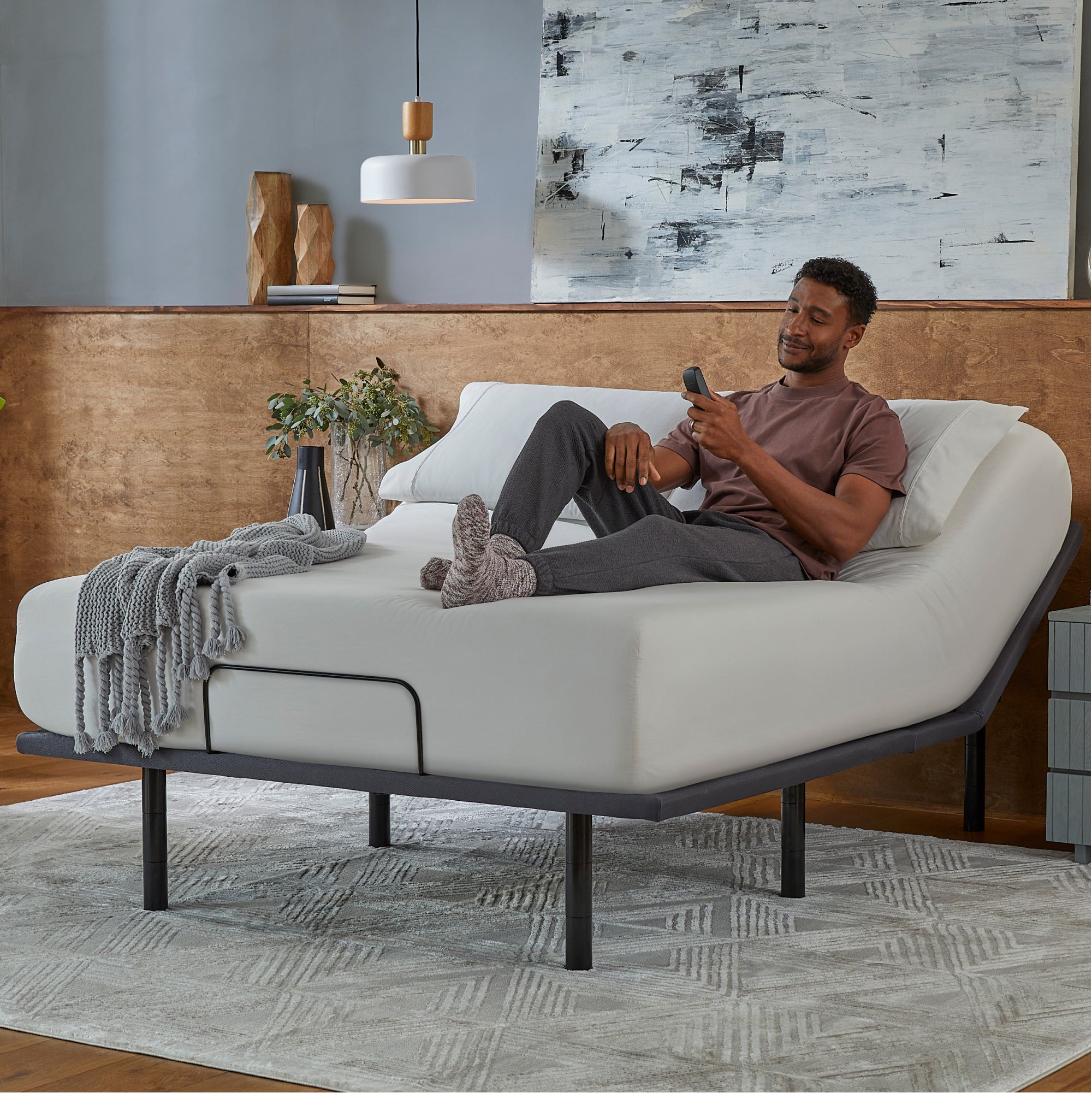 Man sitting in a Baselogic Silver Adjustable Base with a white mattress on top of it.