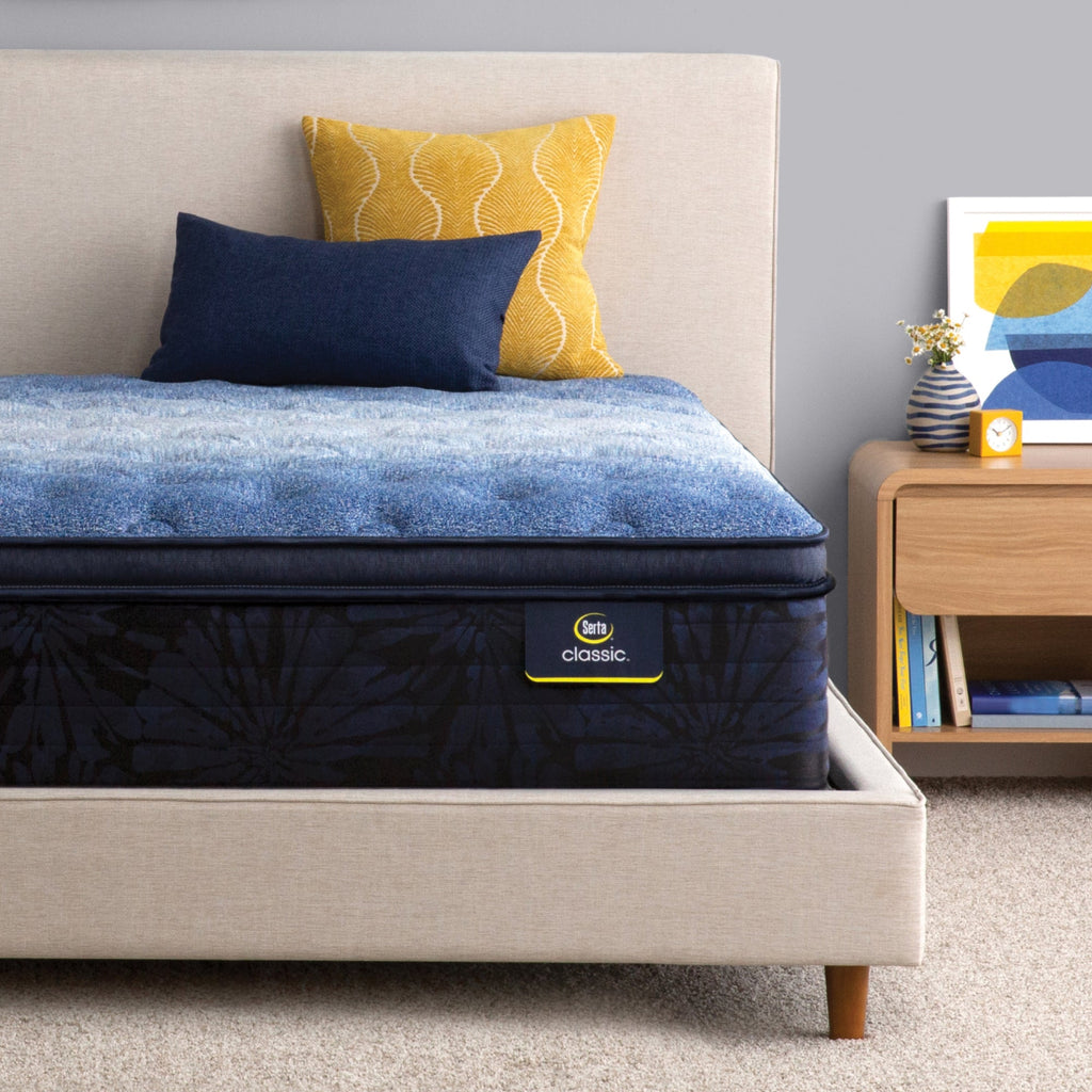 Serta classic brecon plush pillow top mattress sitting in a beige bed frame ||feel: plush pillow top||level: enhanced