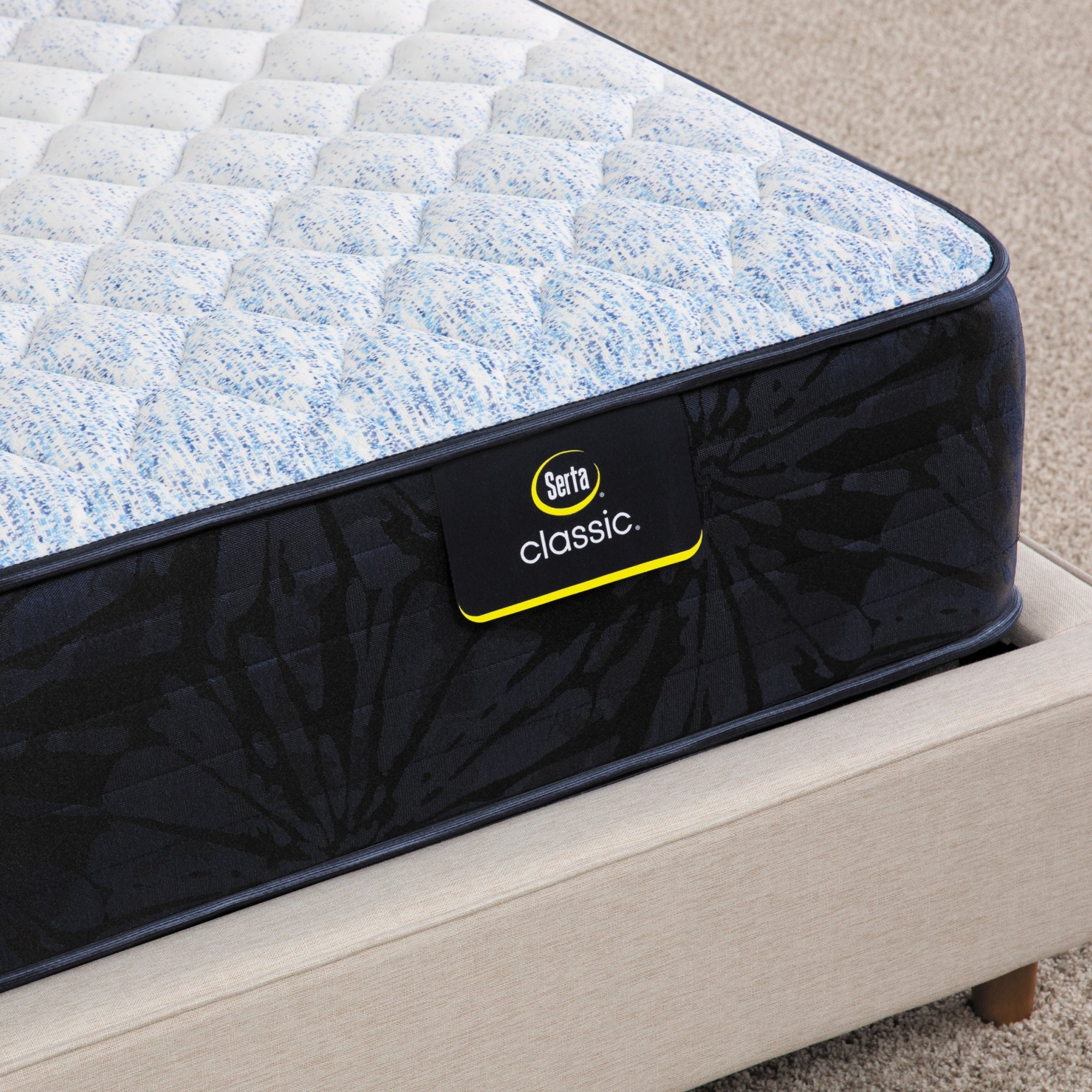 Corner of Serta classic dorian firm mattress sitting in a beige bed frame ||feel: firm ||level: standard