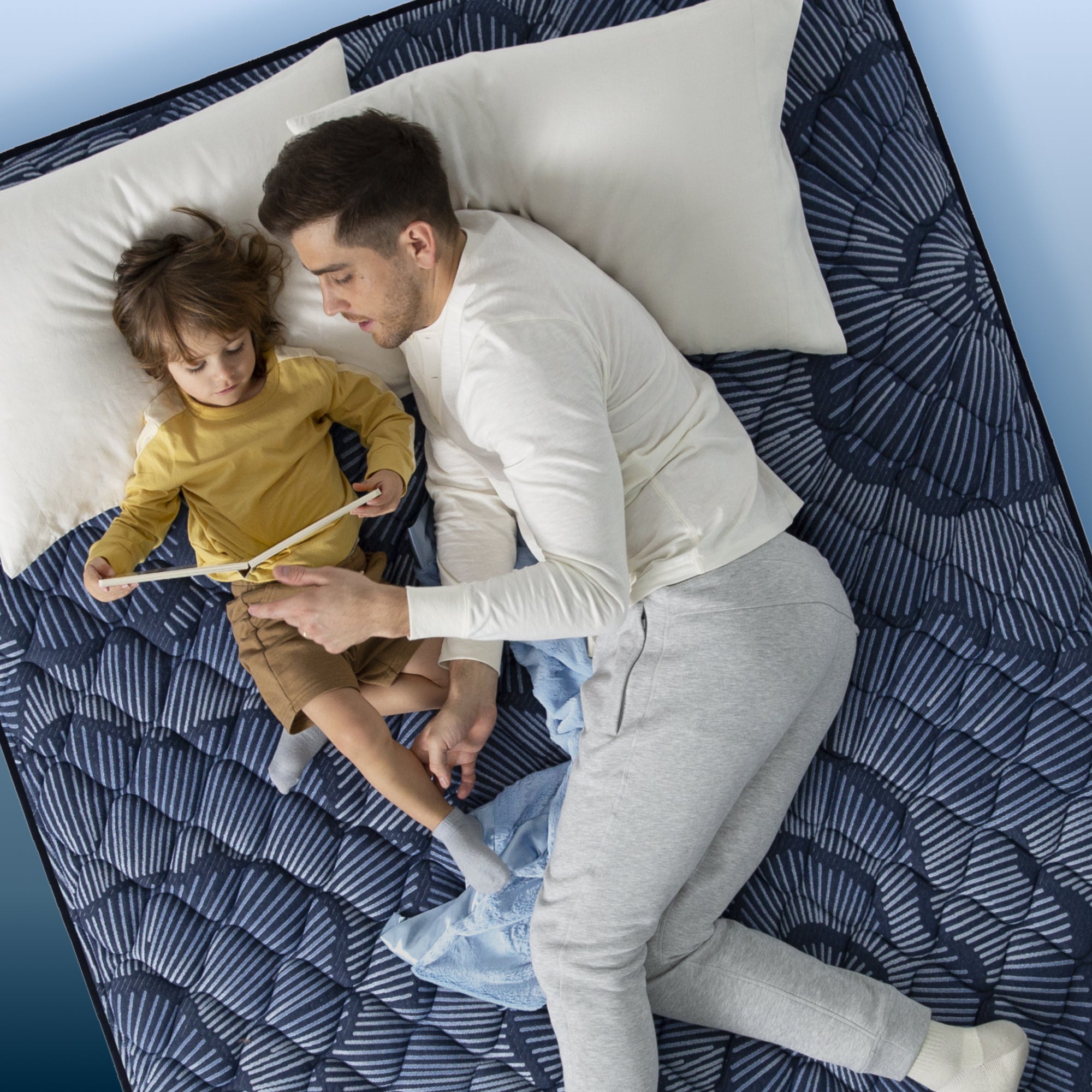 Dad and son reading in bed on a Serta Perfect Sleeper mattress||feel: extra firm||level: ultimate